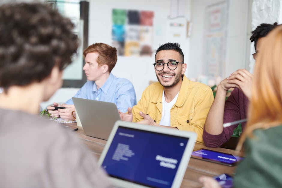 A diverse group discussing a project with laptops in a modern office meeting room